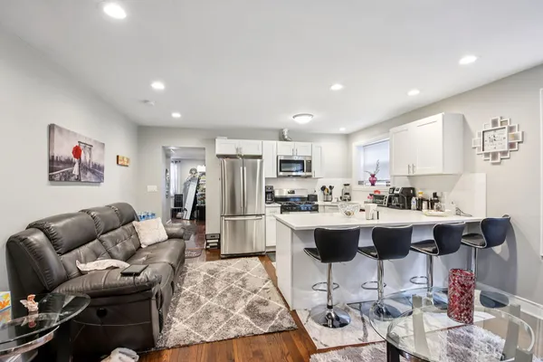 a view of kitchen with stainless steel appliances kitchen island granite countertop a couch and a dining table with rug