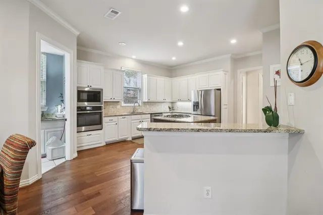 a kitchen with stainless steel appliances granite countertop a refrigerator a stove top oven a sink and dishwasher