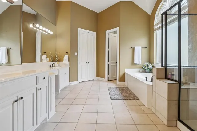 a large bathroom with a double vanity sink a mirror and a bathtub