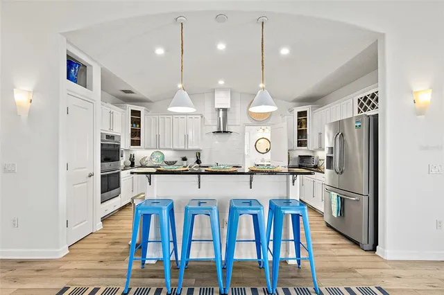 a large kitchen with stainless steel appliances kitchen island granite countertop a table chairs sink and refrigerator