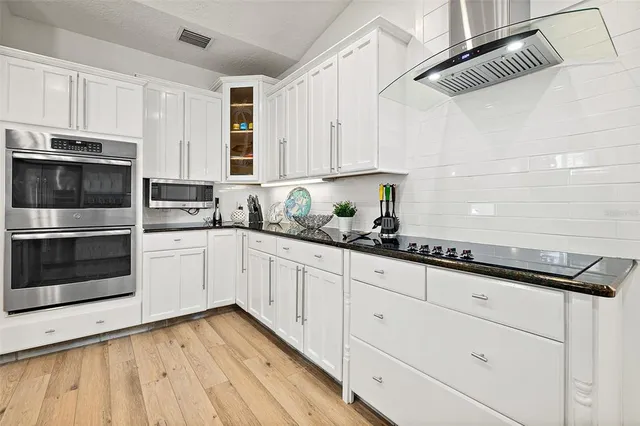 a kitchen with granite countertop white cabinets white stainless steel appliances and sink