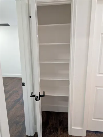 a view of an empty room with wooden floor and closet