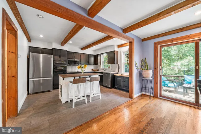 a kitchen with stainless steel appliances kitchen island granite countertop a refrigerator a sink dishwasher a stove and a dining table with wooden floor