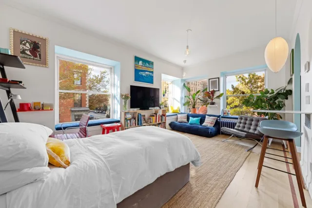 a bedroom with a bed and a flat tv screen next to a large window