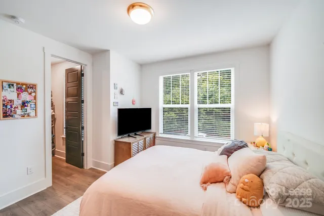 a bedroom with a bed flat screen tv and a window