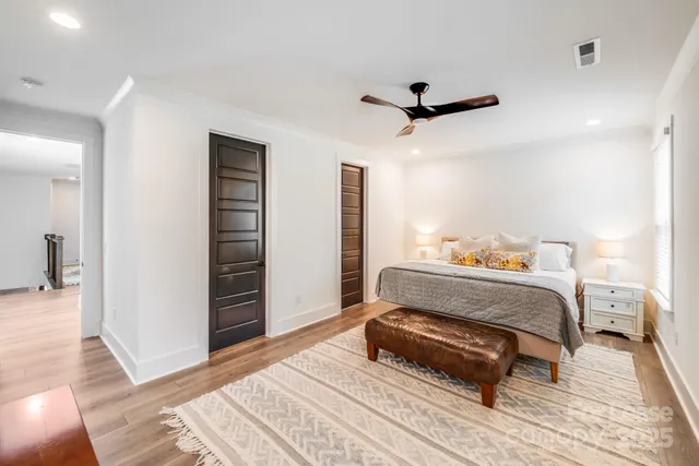 a spacious bedroom with a bed and wooden floor