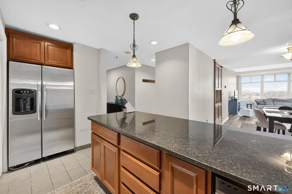 a kitchen with stainless steel appliances granite countertop a sink a refrigerator and a wooden cabinets