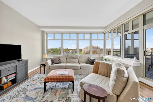 a living room with furniture a flat screen tv and a floor to ceiling window