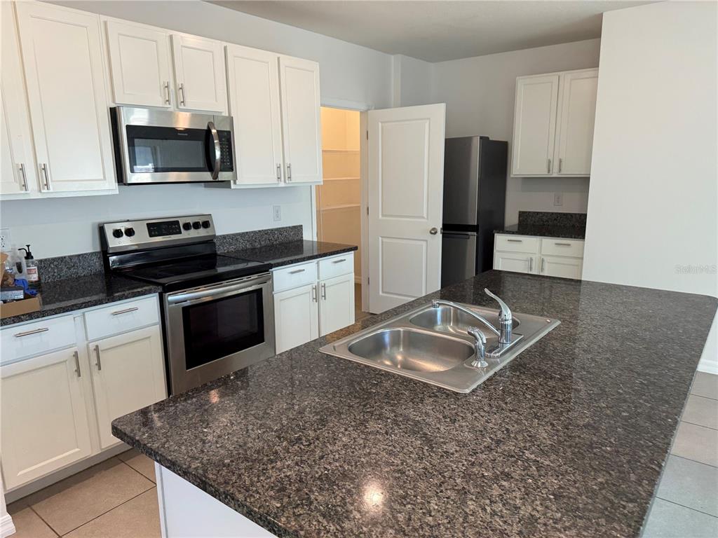 5864 Calla Lilly Drive Sarasota, FL 34232 - Photo 6 of 16 a kitchen with granite countertop a sink stove and refrigerator