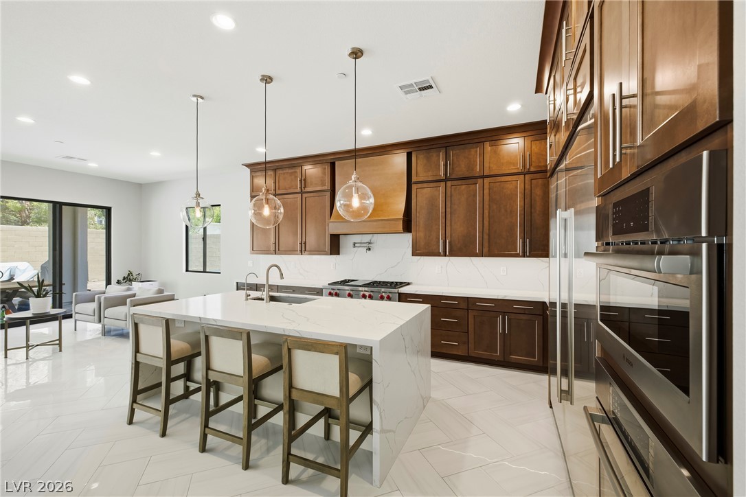 45 Garibaldi Way Henderson, NV 89011 - Photo 15 of 74 Culinary aspirations meet sleek design in this chef's kitchen, featuring a generous island and integrated appliances.