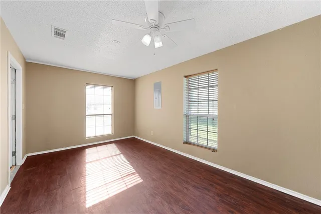 a view of an empty room with wooden floor and a window