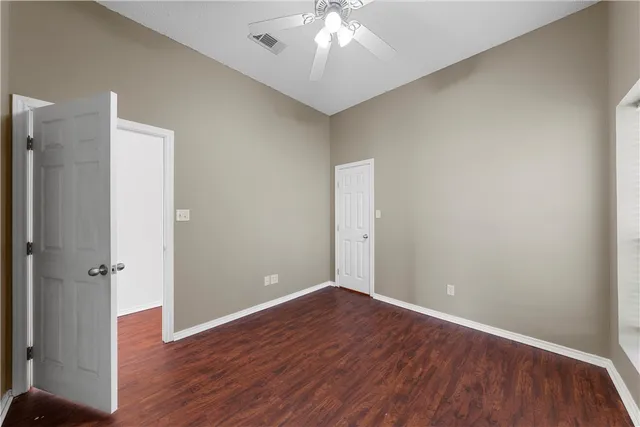 an empty room with wooden floor and a ceiling fan