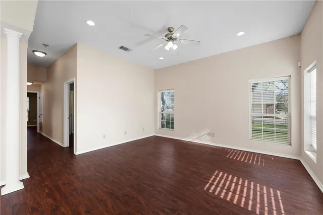 a view of an empty room with wooden floor and a window