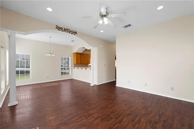 a view of an empty room with wooden floor and a ceiling fan