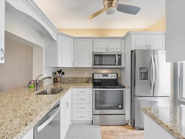 a kitchen with kitchen island granite countertop a sink stove and refrigerator