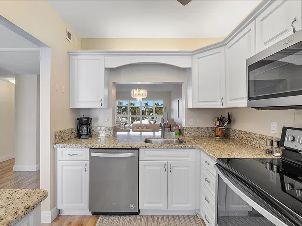 a kitchen with a sink dishwasher a stove and white cabinets