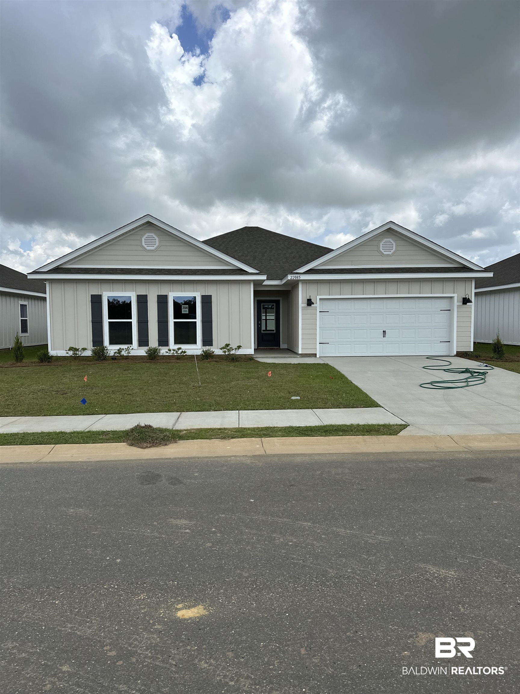 View of front facade with board and batten siding, a front lawn, driveway, and an attached garage