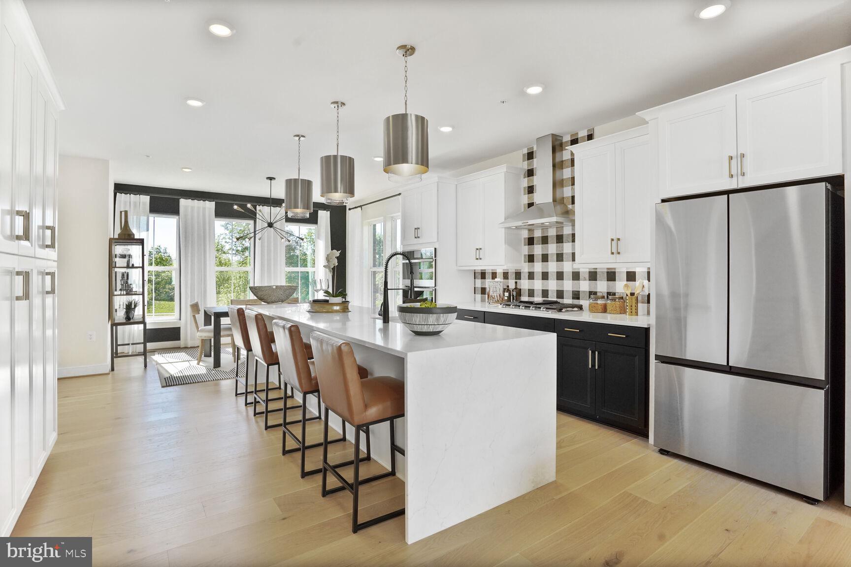 22786 Hanson Overlook Terrace Ashburn, VA 20148 - Photo 4 of 21 a kitchen with stainless steel appliances kitchen island granite countertop a refrigerator a stove top oven and a dining table with wooden floor