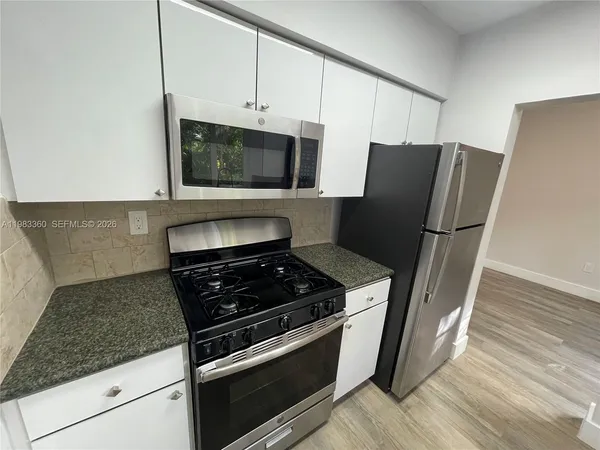 a kitchen with granite countertop a refrigerator stove and microwave