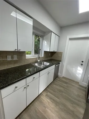 a kitchen with granite countertop a sink window and cabinets
