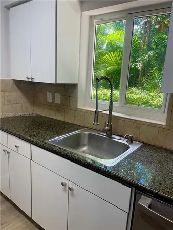 a kitchen with granite countertop sink and window