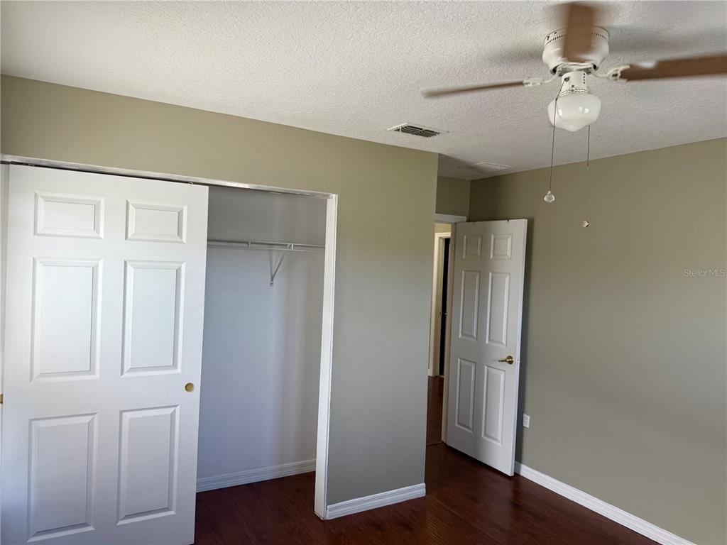 1037 Berkeley Drive Kissimmee, FL 34744 - Photo 17 of 38 an empty room with wooden floor and fan