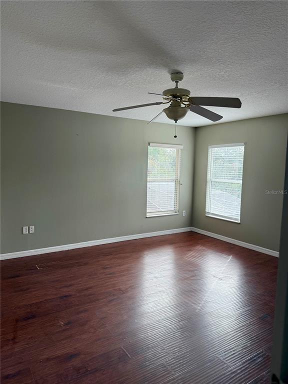1037 Berkeley Drive Kissimmee, FL 34744 - Photo 29 of 38 an empty room with wooden floor ceiling fan and windows