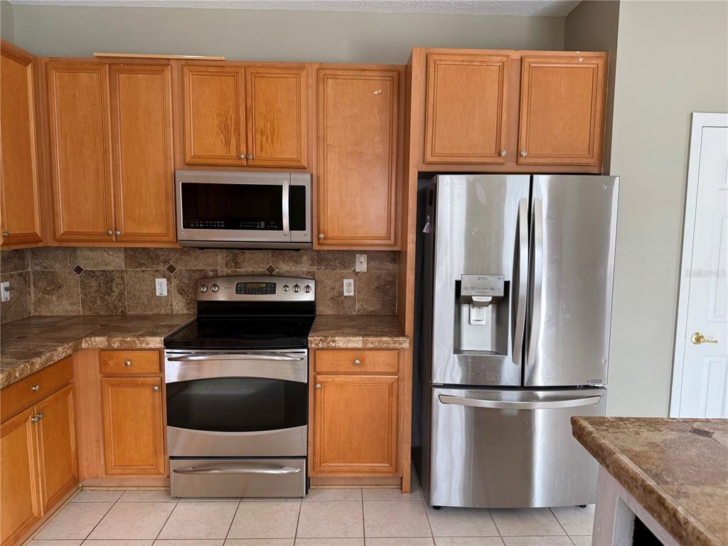 1037 Berkeley Drive Kissimmee, FL 34744 - Photo 7 of 38 a kitchen with granite countertop a refrigerator stove and microwave
