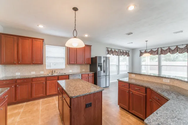 a kitchen with stainless steel appliances granite countertop a sink a stove and a refrigerator