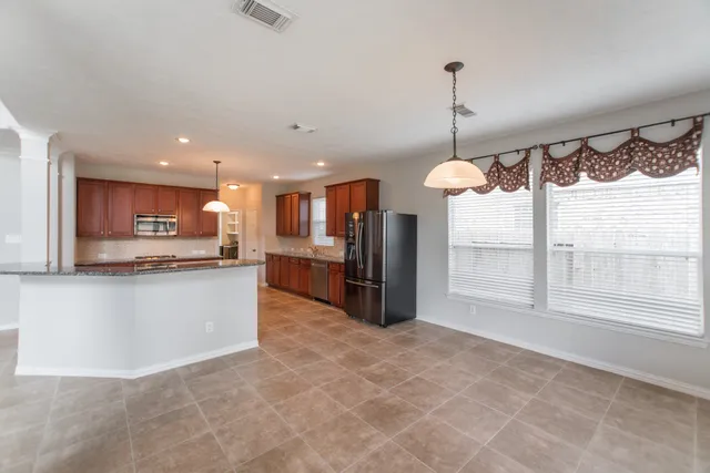a large kitchen with kitchen island a large counter top a refrigerator and cabinets