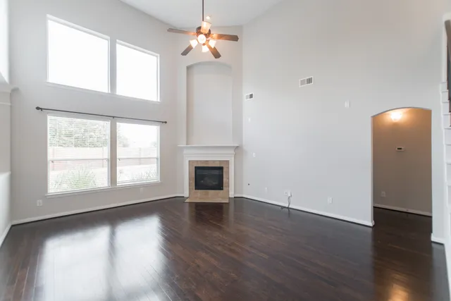 an empty room with wooden floor chandelier and windows
