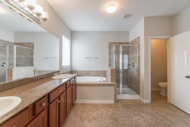a spacious bathroom with a granite countertop sink a toilet a mirror and shower