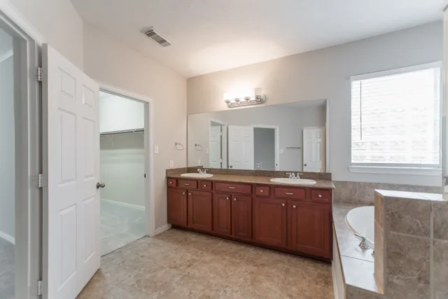 a spacious bathroom with a granite countertop sink mirror and a bathtub