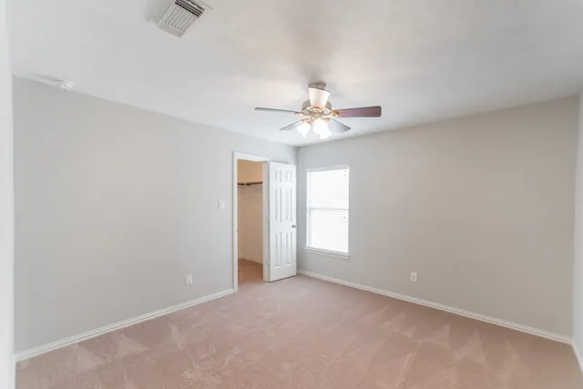 an empty room with windows and fan