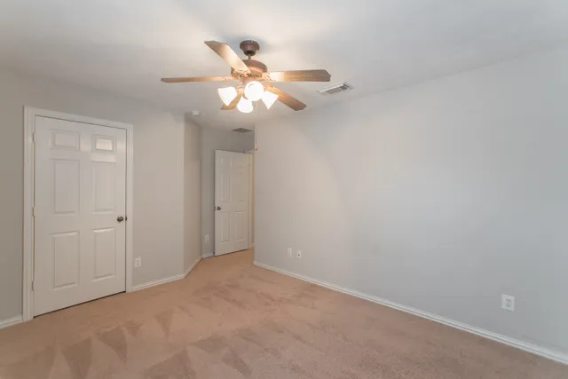 a view of an empty room with a chandelier fan