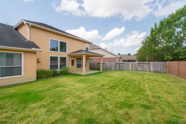 a view of a yard in front of a house with a large tree