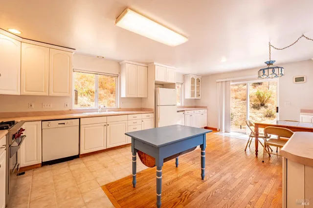 a kitchen with stainless steel appliances granite countertop a stove top oven a sink dishwasher a dining table and chairs with wooden floor