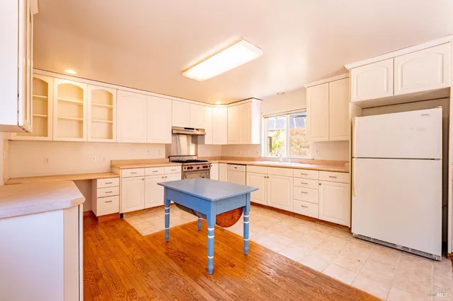 a kitchen with a refrigerator a stove cabinets and wooden floor