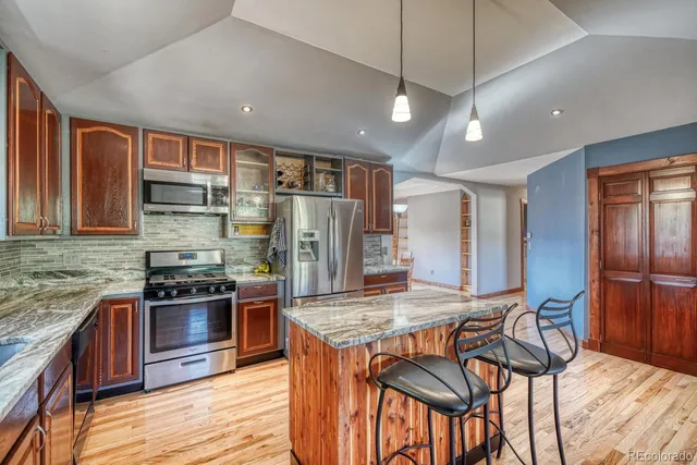 a kitchen with stainless steel appliances granite countertop a stove top oven a refrigerator and wooden cabinets