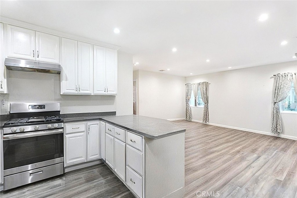 15439 Hart Street Van Nuys, CA 91406 - Photo 27 of 32 a kitchen with white cabinets stainless steel appliances and wooden floor