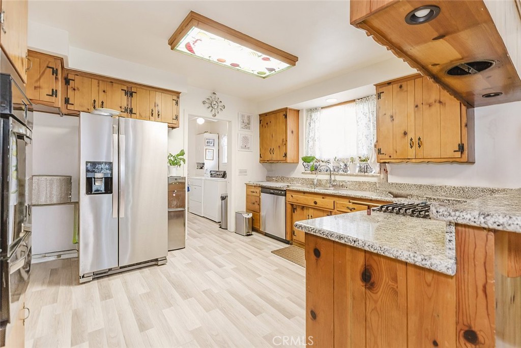 15439 Hart Street Van Nuys, CA 91406 - Photo 6 of 32 a kitchen with stainless steel appliances granite countertop a refrigerator a sink dishwasher a stove with wooden cabinets and floor