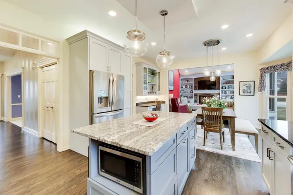 a kitchen with stainless steel appliances granite countertop a kitchen island a stove and a dining table with wooden floor