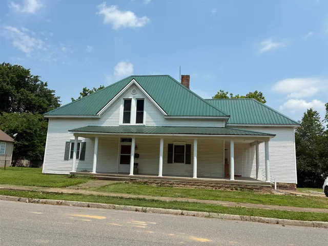 a front view of a house with a garden and trees