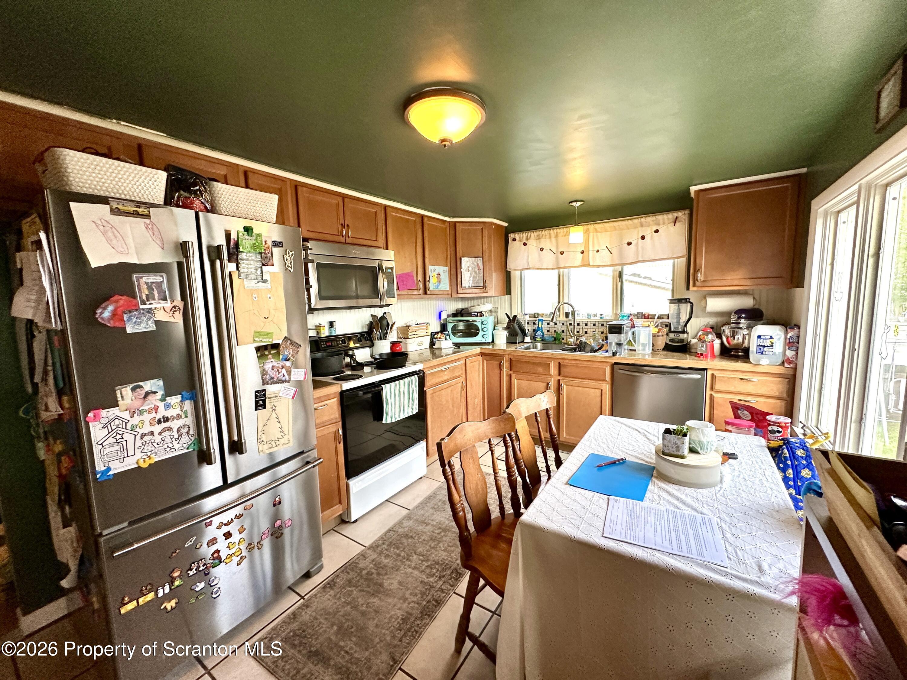 544 Green Street Duryea, PA 18642 - Photo 2 of 14 a kitchen with stainless steel appliances granite countertop a refrigerator a stove top oven and a dining table with wooden floor