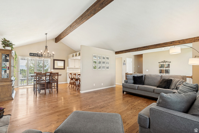 9832 Falconhurst Drive Sandy, UT 84092 - Photo 4 of 29 Spacious living area featuring vaulted ceilings with exposed wood beams, wood-finish flooring, and natural light from patio doors with plantation shutters