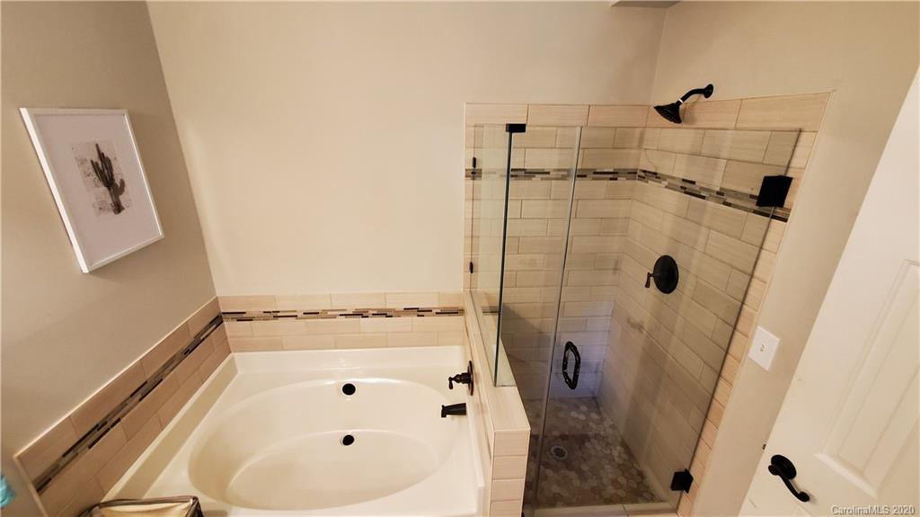 20700 Willow Pond Road Cornelius, NC 28031 - Photo 33 of 47 a bathroom with a white tub a vanity and a shower