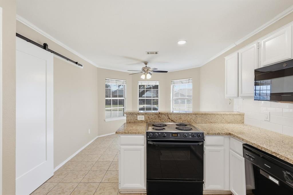 7733 Liz Lane Watauga, TX 76148 - Photo 8 of 27 Kitchen featuring a peninsula, a barn door, black appliances, white cabinetry, and a ceiling fan