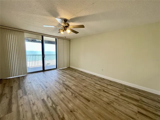 an empty room with wooden floor fan and windows