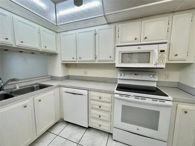 a kitchen with white cabinets and appliances