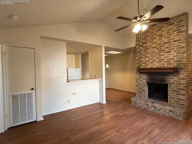 a view of an empty room with wooden floor a fireplace and a window